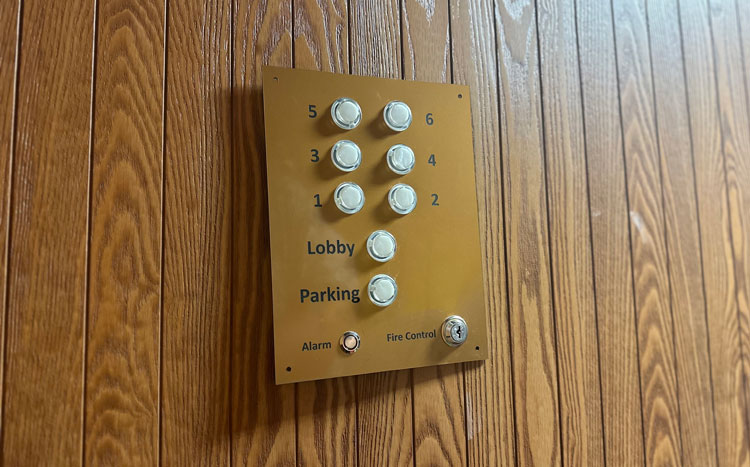 Wood panel wall with elevator buttons.