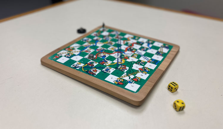 A vintage game of chutes and ladders, with two 6-sided die sitting on a table.