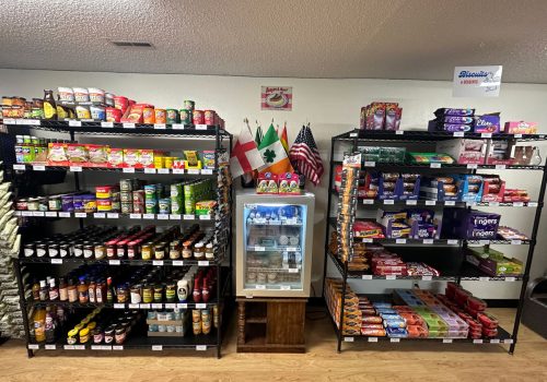 Shelves and small refrigerator lining a wall, filled with various food items from Britain.
